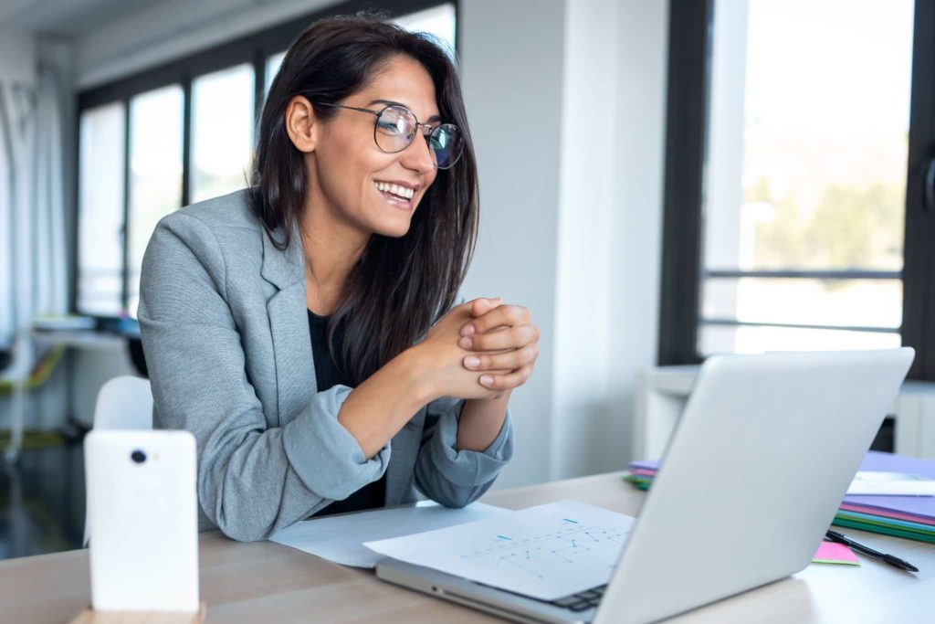 Woman looking at computer and smiling during virtual work.
